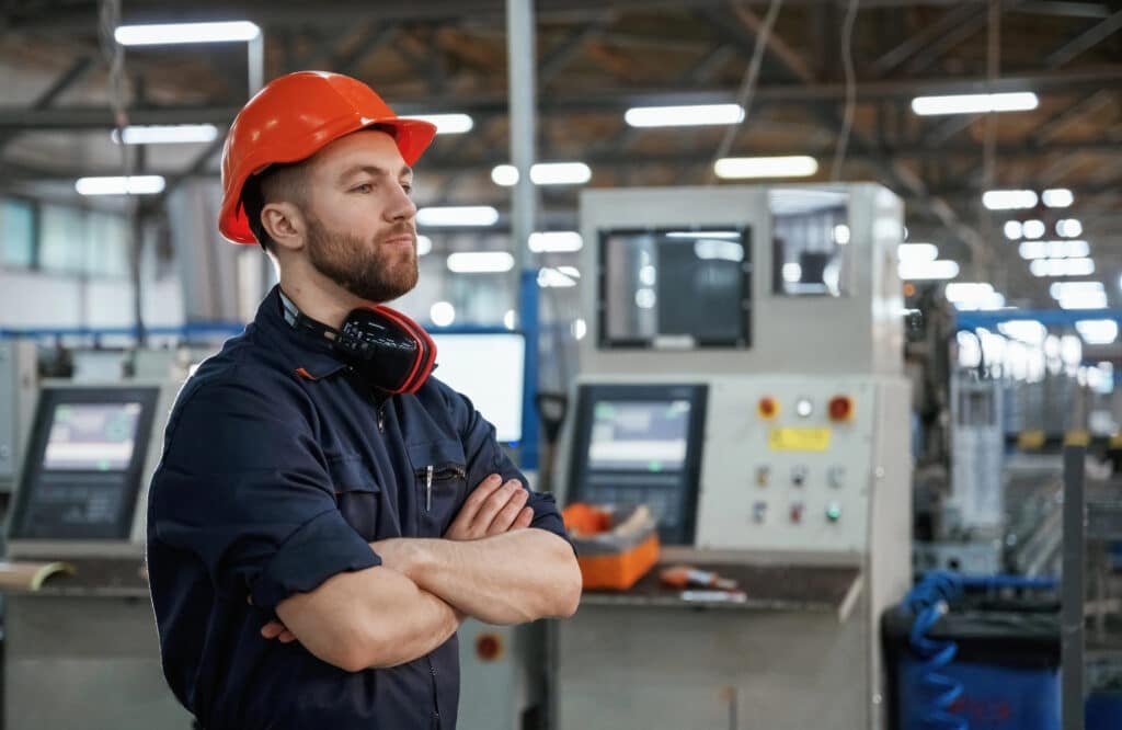 Plant manager reviewing staffing costs and turnover on a clipboard in a manufacturing facility
